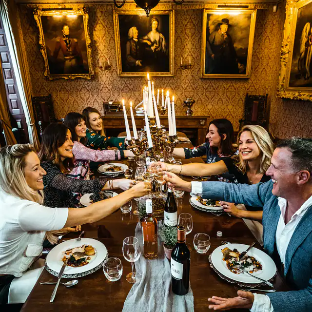 Friends raising their glasses at a candle-lit festive dinner table